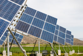 low angle of solar panels in field with mountains in the background