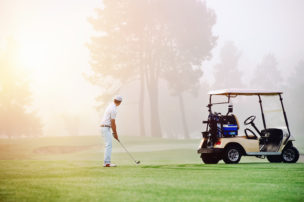 Person golfing with golf cart in picture