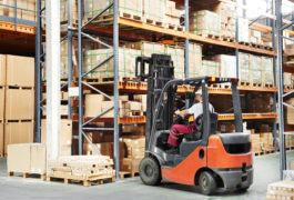 Worker driving forklift in warehouse